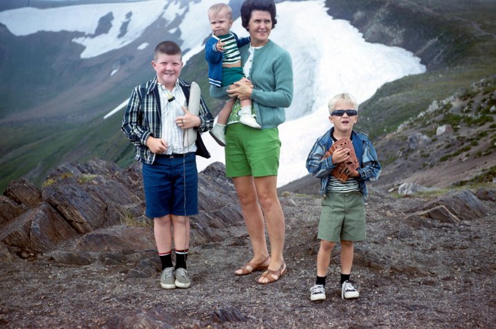 A rare photo of Mom with all three sons.  Your author is on the right.  Note my dutiful older brother holding the purse and bottle.